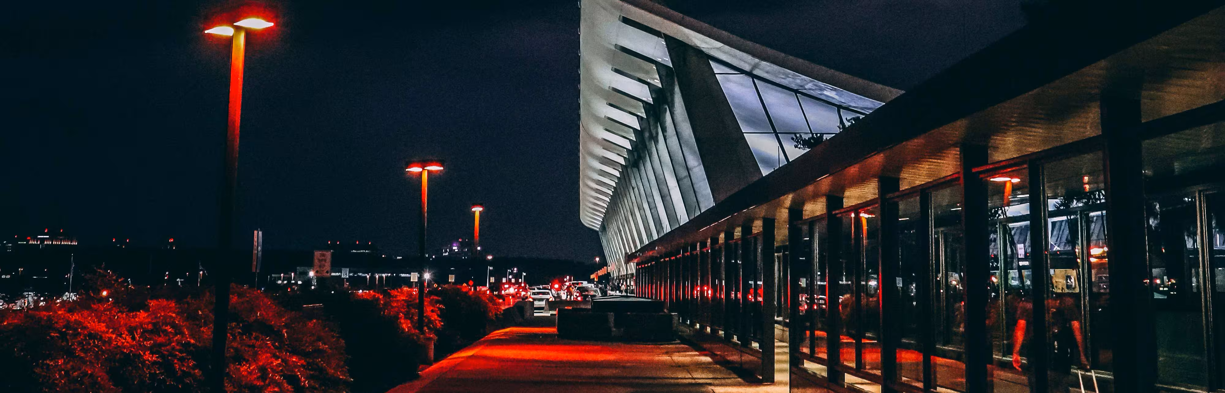 Airport terminal kerb at night with red lights along the walkway
