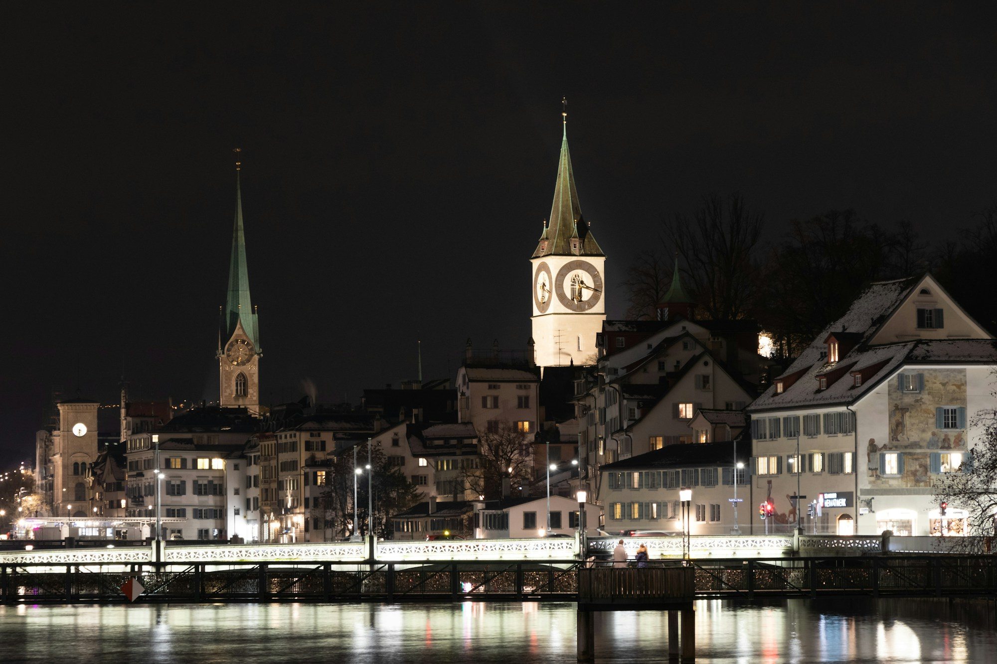 Zurich airport transfer: Zurich's old town and church spires lit up along the Limmat at night