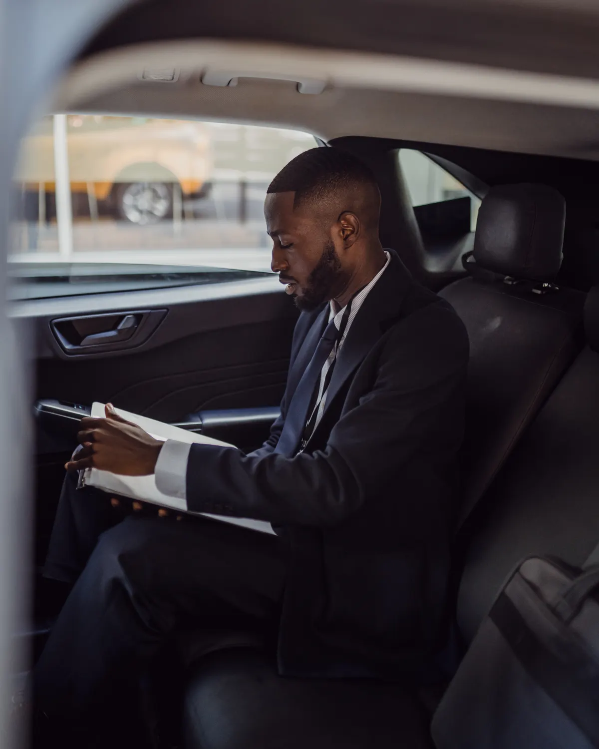 Executive reviewing documents in the rear seat of a chauffeured car